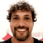 Alessandro Rolli, autor e fundador do melhores fitness, moreno sorrindo com cabelo cacheado e barba curta